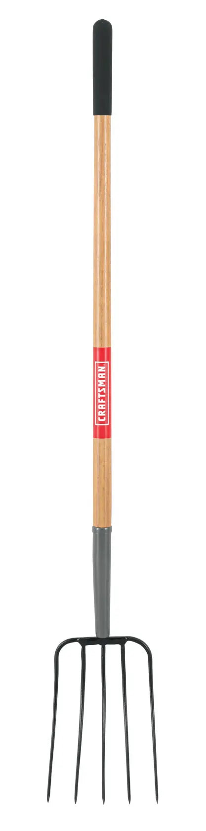A garden pitchfork with a long wooden handle and four metal tines, featuring a black grip at the top and a red label on the handle.